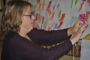 Photo of teacher putting post-it-note on board.