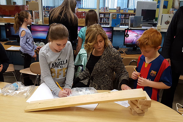 teacher works with students to construct simple machines