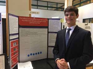 Student poses in front of his research display