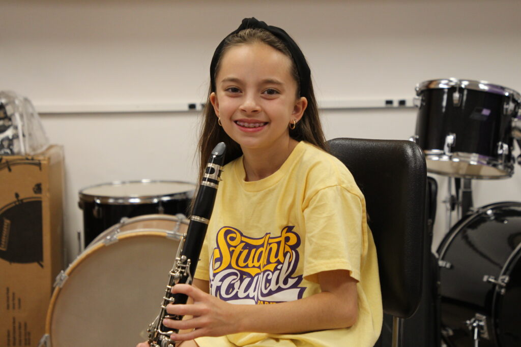 Elizabeth Crispino in a yellow Student Council shirt and holding a clarinet