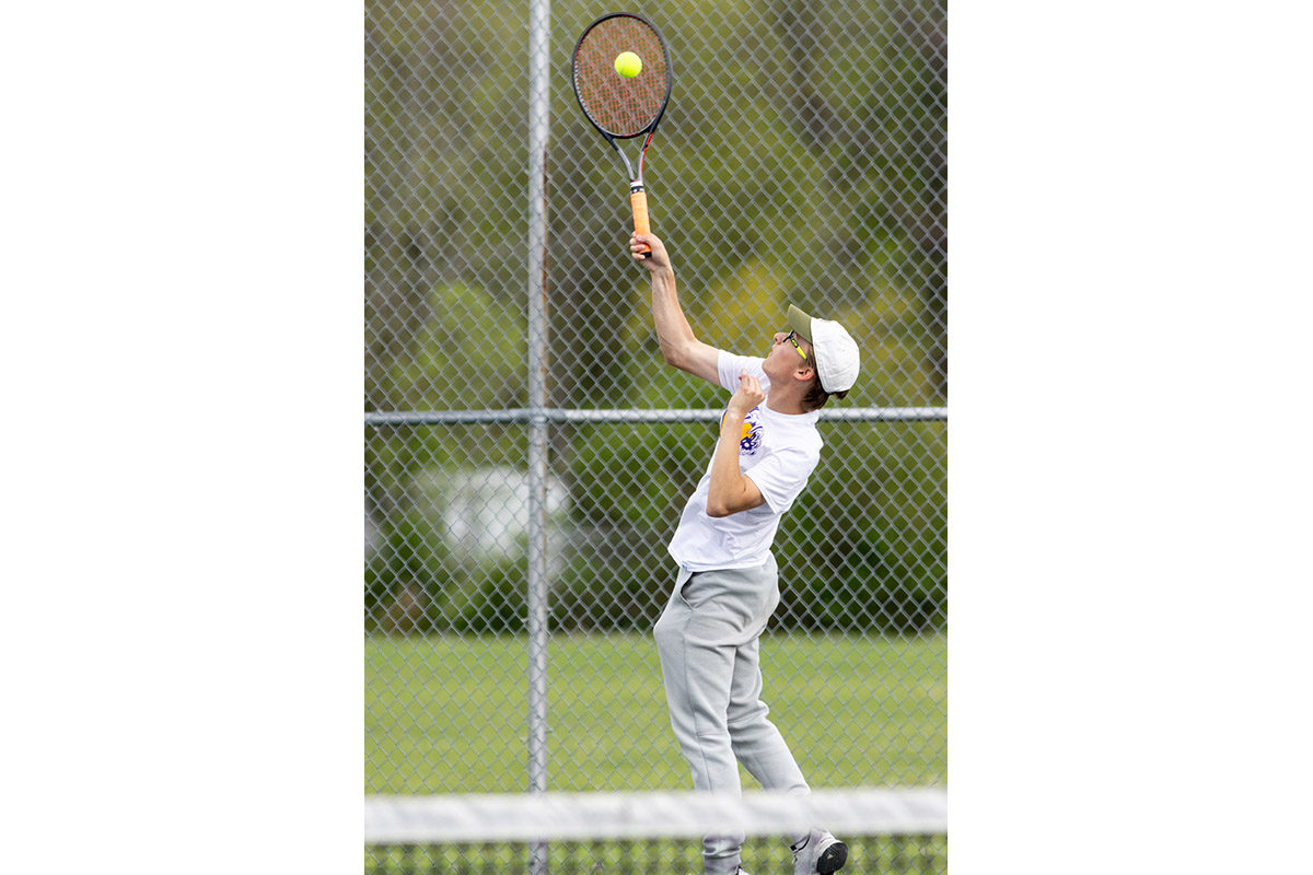 A Warwick Valley High School varsity boys tennis player hits the ball.