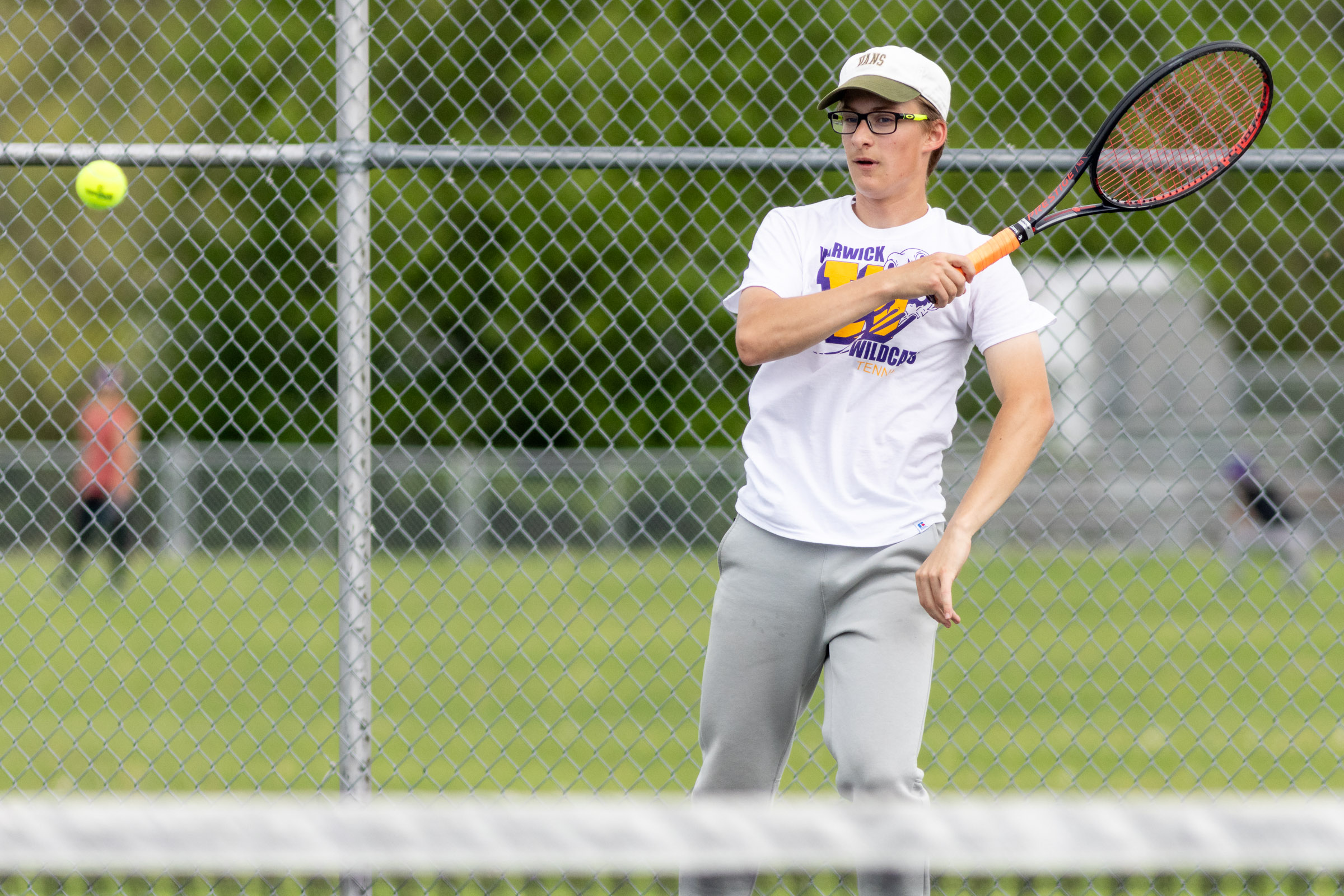 A Warwick Valley High School varsity boys tennis player hits the ball.