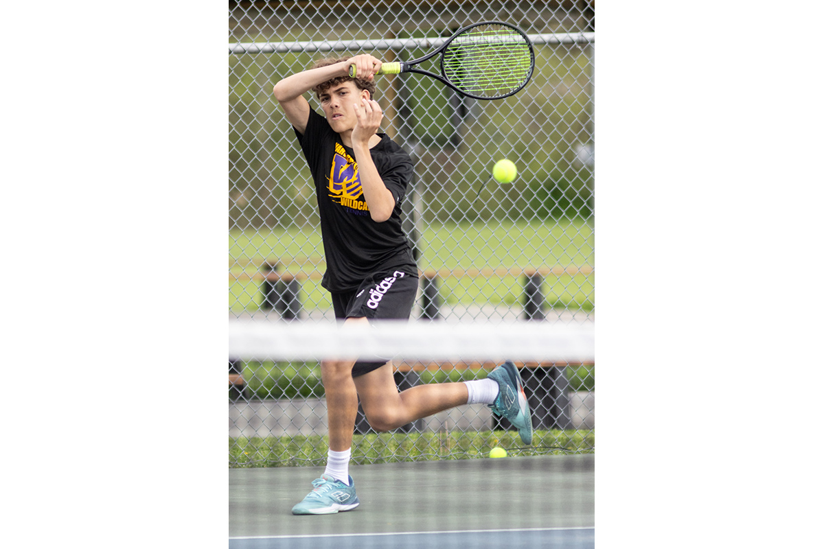 A Warwick Valley High School varsity boys tennis player hits the ball.