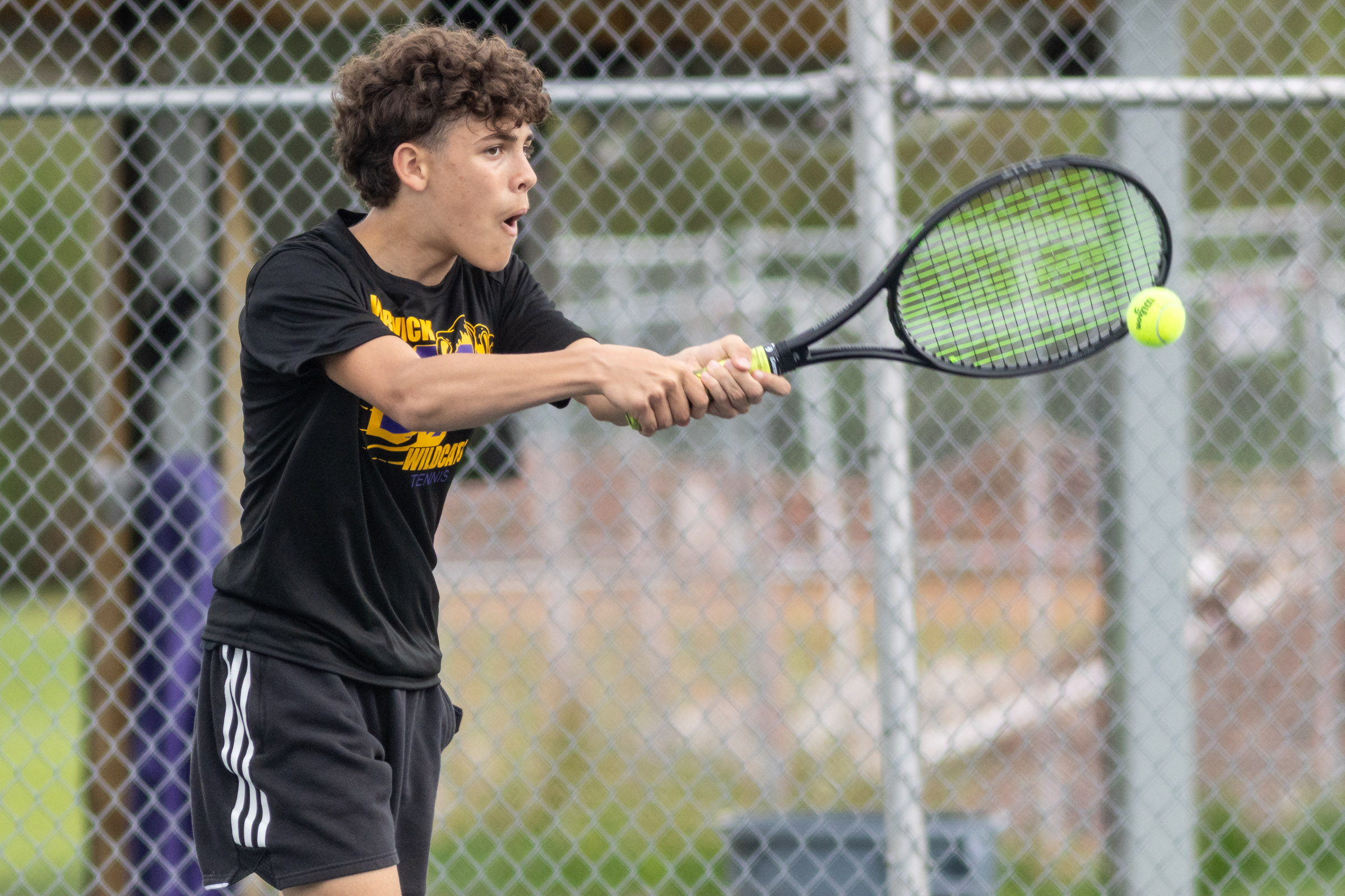 A Warwick Valley High School varsity boys tennis player hits the ball.