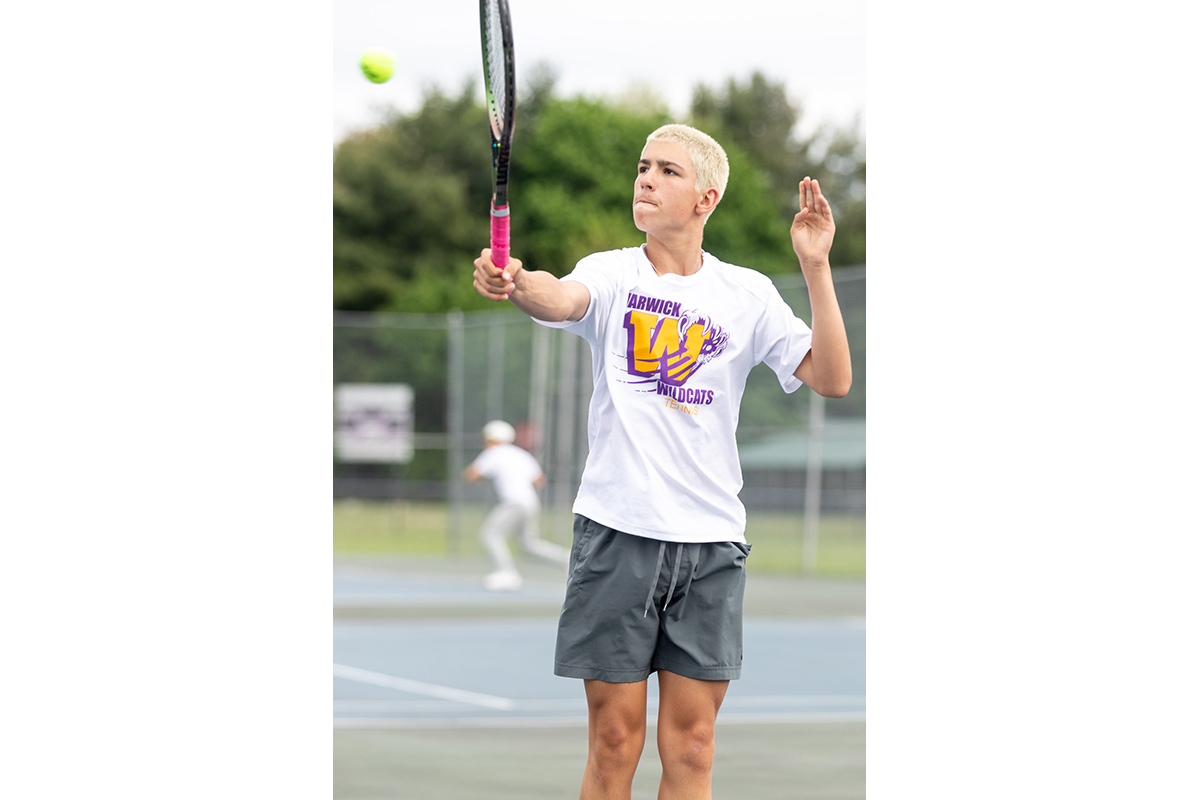 A Warwick Valley High School varsity boys tennis player hits the ball.