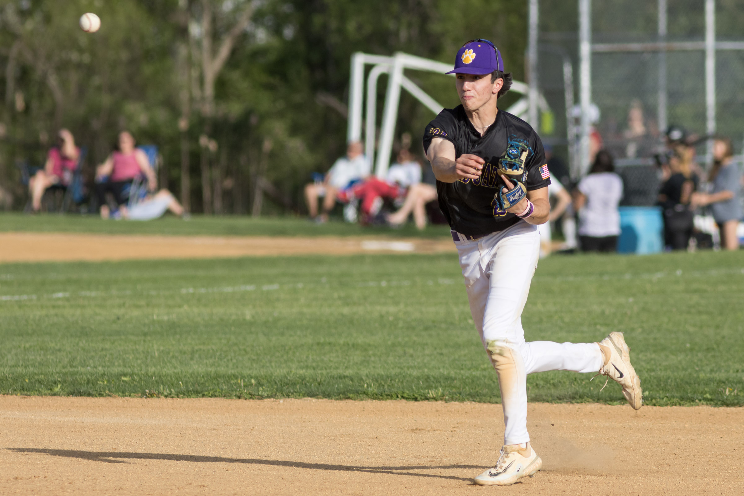 A Warwick Valley High School varsity baseball infielder throw the ball to first base.