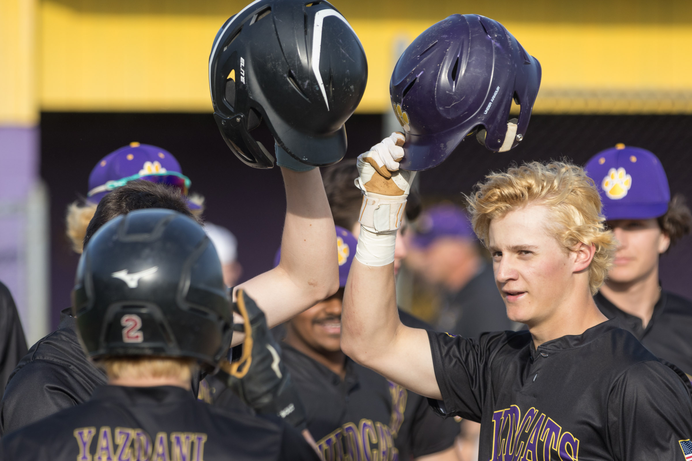 A Warwick Valley High School varsity baseball player raises his batting helmet in celebration after hitting a home run.