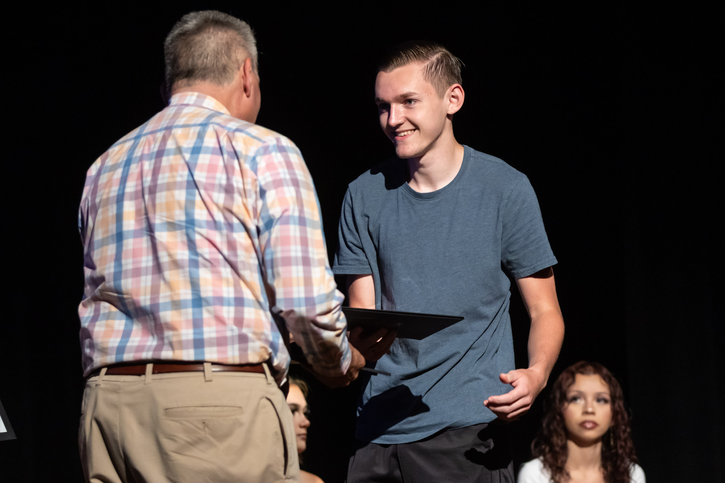 A students gets his NTHS certificate from a teacher on stage during the Warwick Valley High School Career and Technical Education Recognition Ceremony and Honor Society Induction