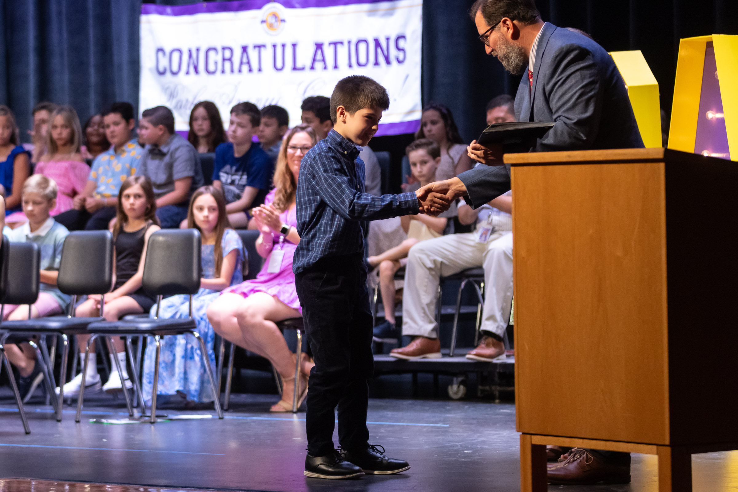 A students shakes hands with principal William Biniaris on stage during the Park Avenue Elementary School Fourth Grade Moving Up Ceremony in the WVHS auditorium