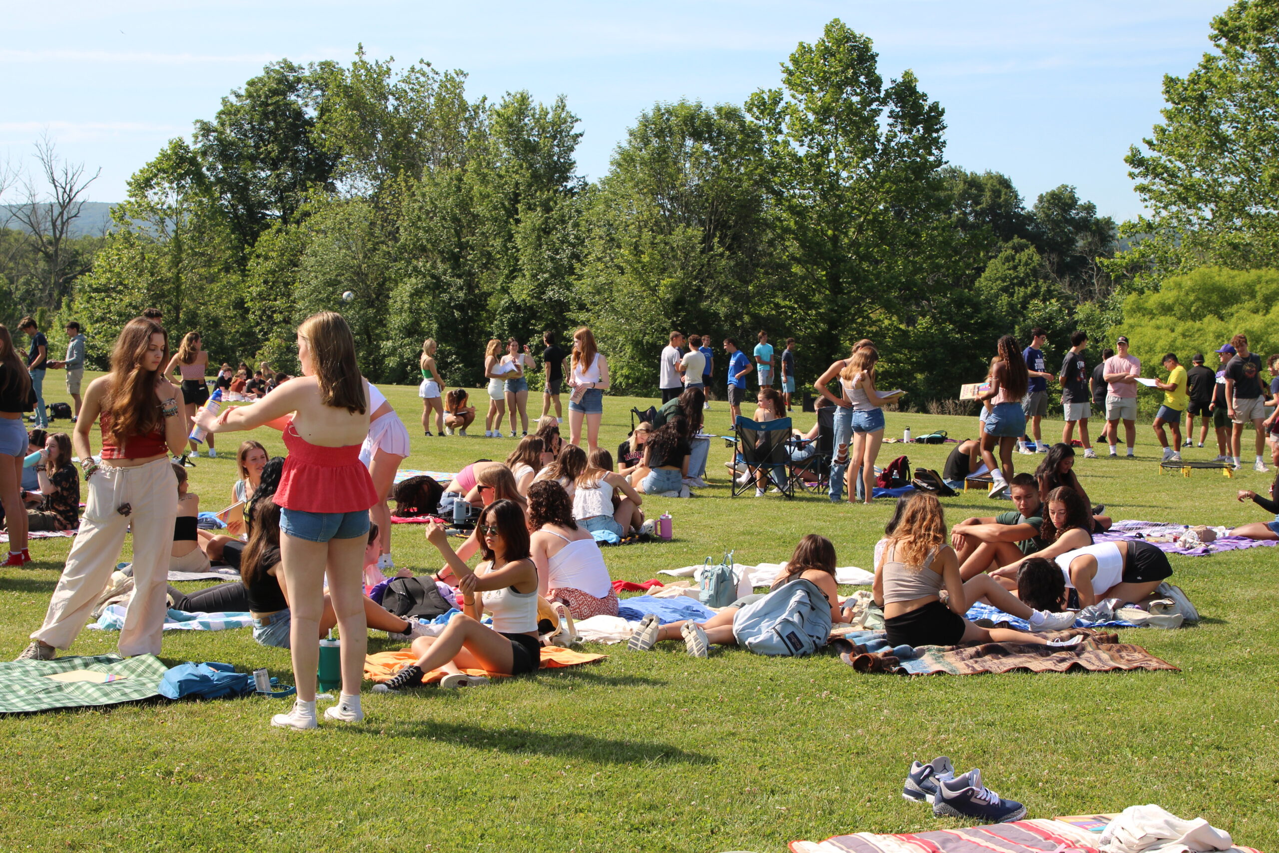 Warwick Valley High School seniors sit on blankets on the grass while other stand during their Senior Picnic