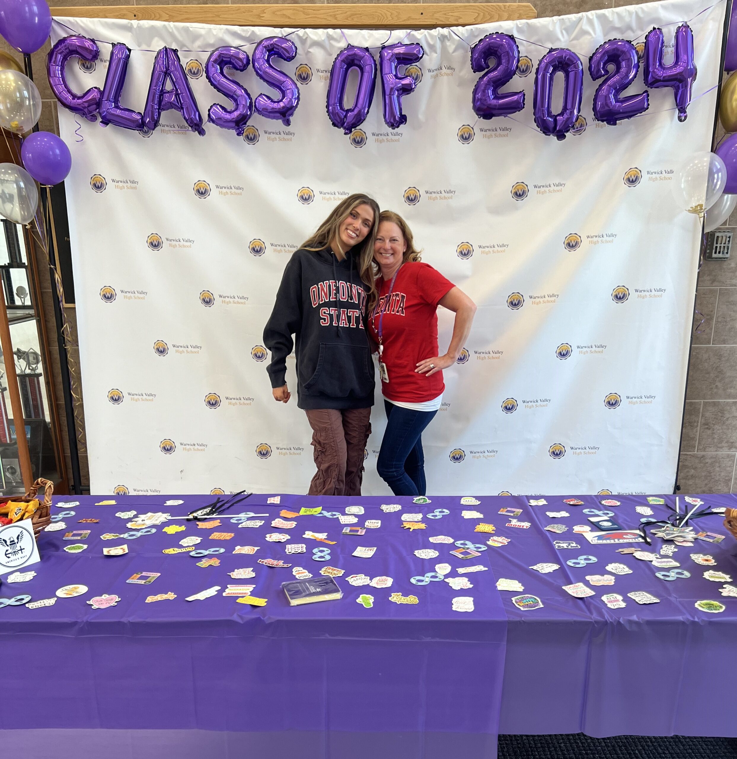 A WVHS senior and a staff member stand under balloons reading "Class of 2024" and holds a sign reading "I'm Ready to Get to Work On Day One" on Decision Day, celebrating the Class of 2024 and the choices they’ve made about their post high school lives.