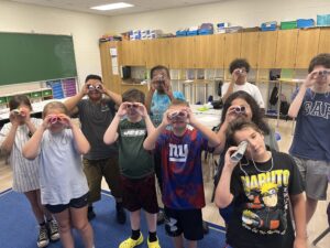 An extended school year program photo of students using the binoculars they made