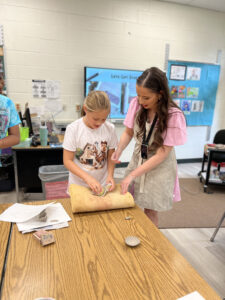 teacher helping student make pottery