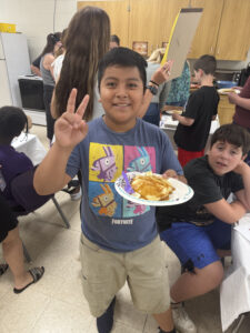 student smiling while holding plate of food