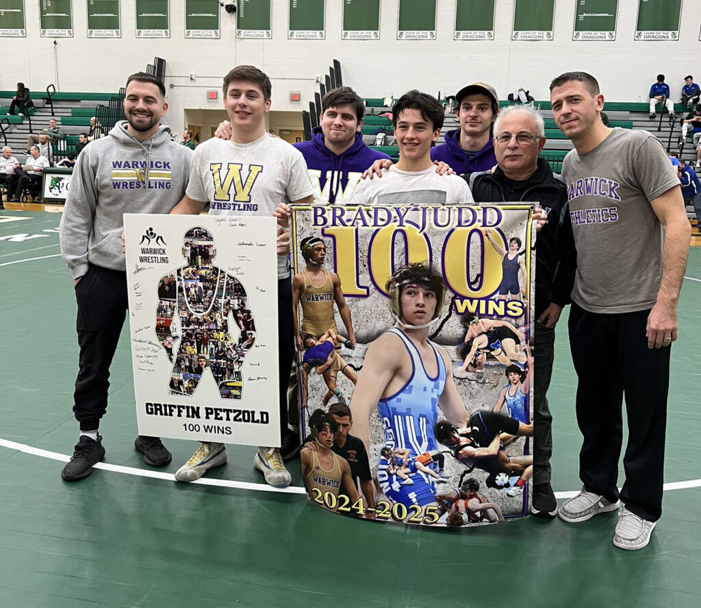 Wrestlers Griffin Petzold and Brady Judd with posters celebrating their 100th career wins at the Cornwall Duals.