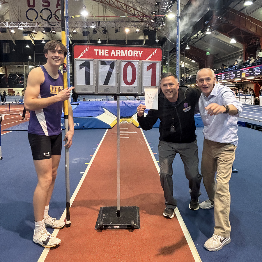 Record-setting pole vaulter with coaches at indoor track meet.